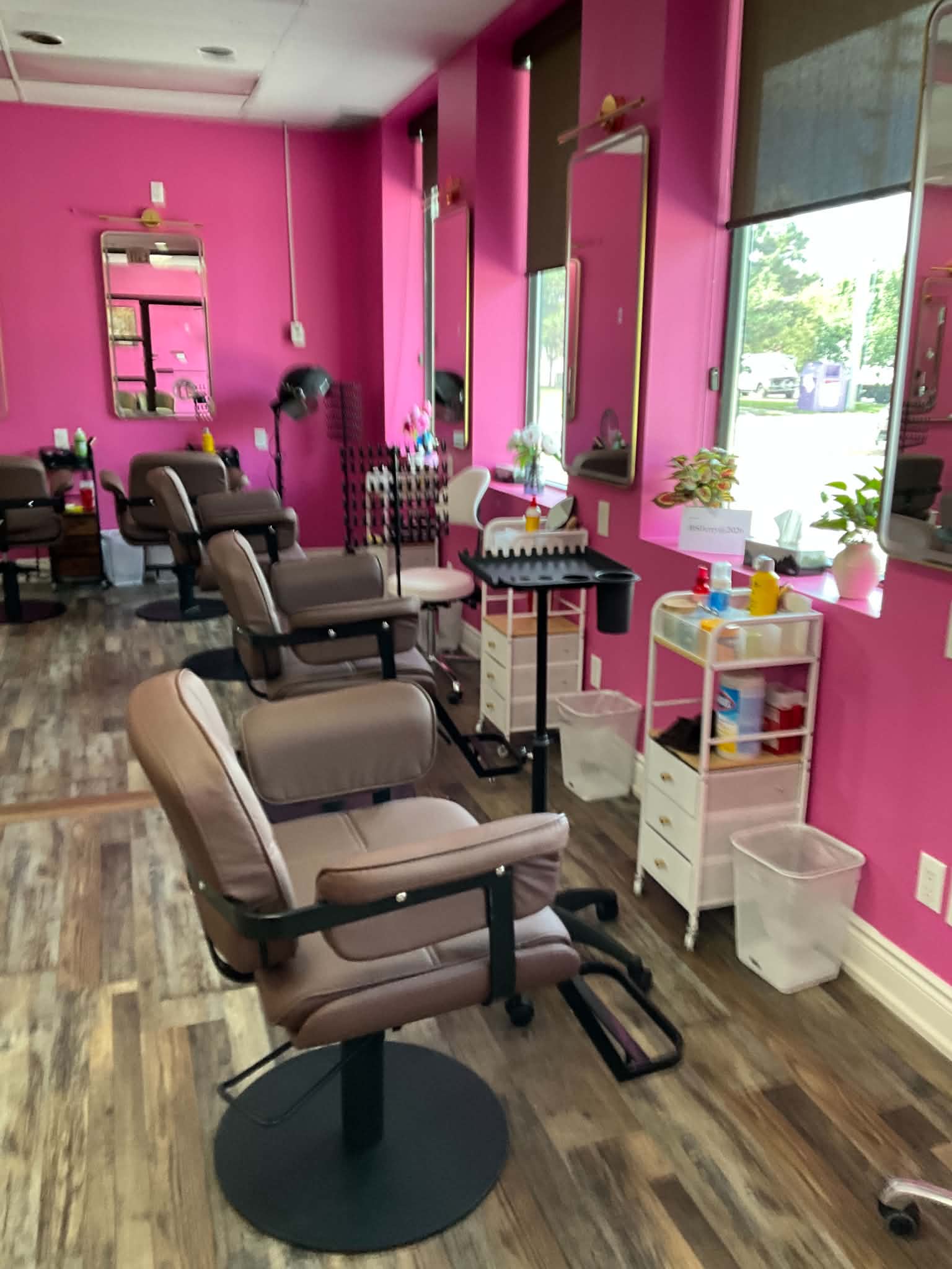 Row of styling stations with gold-framed mirrors along the pink wall